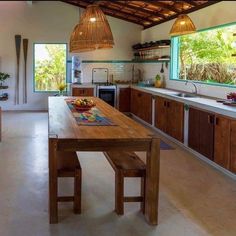 an open kitchen with wooden cabinets and counter tops, along with a dining table in the center