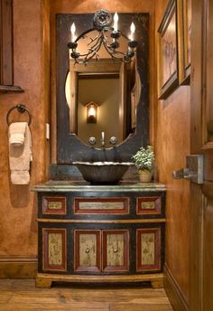 a bathroom with a sink, mirror and wooden cabinetry in it's center