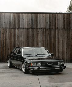 a black car parked in front of a wooden fence