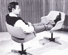 a black and white photo of a man sitting in a chair with his feet up