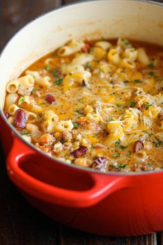 a red pot filled with macaroni and cheese on top of a wooden table