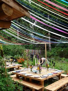 an outdoor dining area with wooden tables and colorful streamers