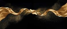two gold wavy lines are flying in the air with dust coming out of them on a black background