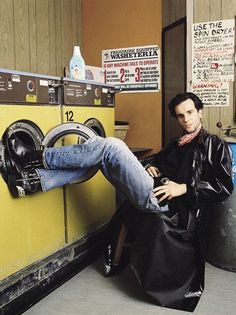 a man sitting in front of a washer next to a dryer and drying machine