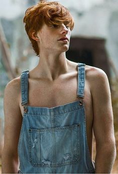 a man with red hair and overalls looking off into the distance