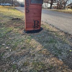 an outhouse on the side of a road with graffiti written on it's door