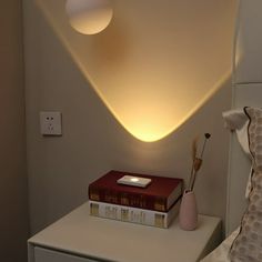 a nightstand with books and a lamp on it