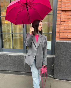 a woman holding an umbrella on the sidewalk