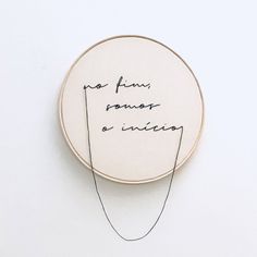 a handwritten quote on a white wall hanging from a hoop with black thread in it