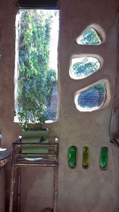 a bathroom with green glass bottles on the wall and windows in the walls, along with a sink