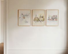 three paintings hang on the wall above a bed in a room with white walls and wood floors