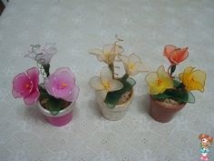 three small vases with flowers in them on a white tablecloth covered table cloth