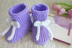 two crocheted baby booties sitting next to a book