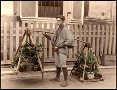 an old photo of a man standing next to some potted plants