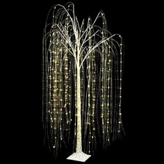 a tall white tree with lots of lights on it's branches in the dark