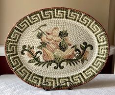 a mosaic plate with flowers on it sitting on a bed in a room next to a wall