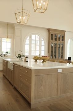 a large kitchen with wooden floors and white walls, along with an island in the middle