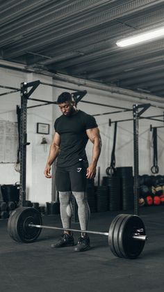 a man standing next to a barbell in a gym