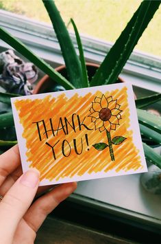 a hand holding up a card that says thank you with a sunflower on it