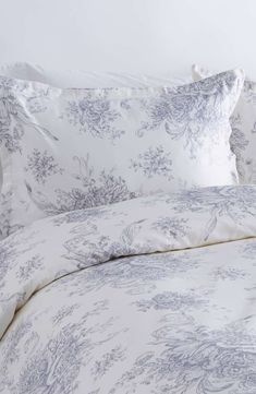 the comforter is made up with blue and white floral designs on it, along with two pillows