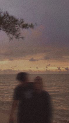 two people walking on the beach at sunset