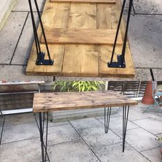 three wooden tables with hairpin legs are on the ground next to some potted plants