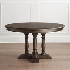 a round table with two wooden legs and a glass top sits on a hard wood floor