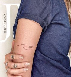 a woman with a small wave tattoo on her arm