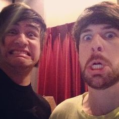 two men standing next to each other in front of a red curtain with their mouths open