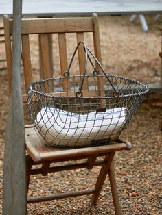 a metal basket sitting on top of a wooden chair next to a park bench with benches in the background