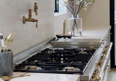 a stove top oven sitting inside of a kitchen next to a vase filled with flowers