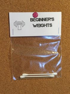 there is a bag with two white toothbrushes in it on the floor next to a sign that says beginner's weights