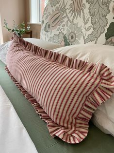 a striped pillow on top of a bed next to a white and green comforter