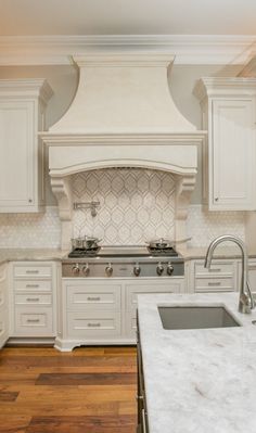 a large kitchen with white cabinets and marble counter tops, along with an island in the middle