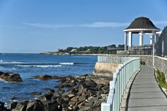 a walkway next to the ocean with a gazebo in the background