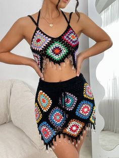 a woman wearing a colorful crochet top and shorts with her hands on her hips