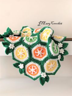 a crocheted pot holder with oranges, lemons and green leaves on it