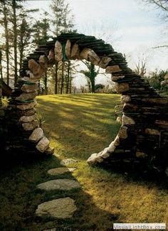 an arch made out of rocks in the grass