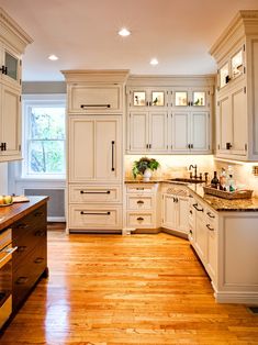 a large kitchen with white cabinets and wood flooring, along with an island in the middle