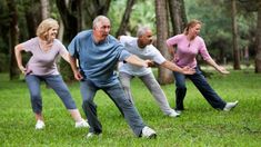 an older man and two women are playing tugo ball in the park with each other