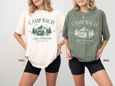 two women standing next to each other in shorts and t - shirts with camp bach on them