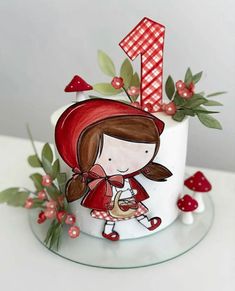 a white cake with red decorations and a girl holding a cup on top of it