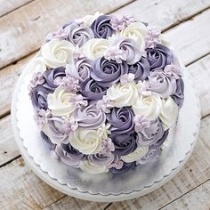 a white and purple cake sitting on top of a wooden table covered in frosting