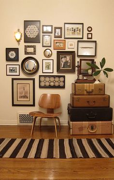 there is a wall with many pictures on it and a chair in front of some suitcases