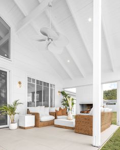 an outdoor living area with wicker furniture and large windows on the side of the house