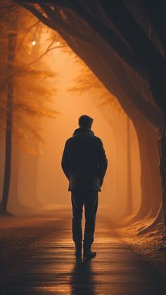 a man walking down a road in the middle of a foggy forest at night