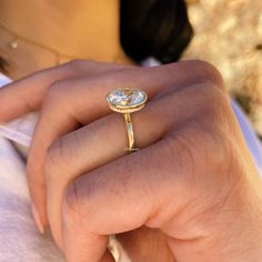 a close up of a person wearing a ring with an oval shaped diamond on it