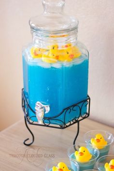 blue liquid with yellow rubber ducks in it and four small plastic cups filled with them