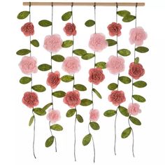 some pink flowers and green leaves hanging from a wooden frame on a white wall ornament