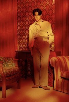 a woman standing next to a chair in a room with red walls and patterned curtains